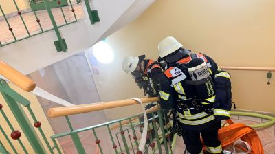 Feuerwehrleute auf der Treppe, Schläuche verlegt
